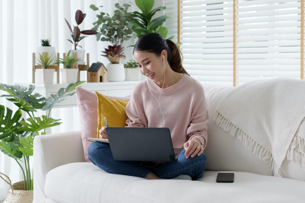 Cozy relax young attractive asian female employee wear earphone listen to digital online course