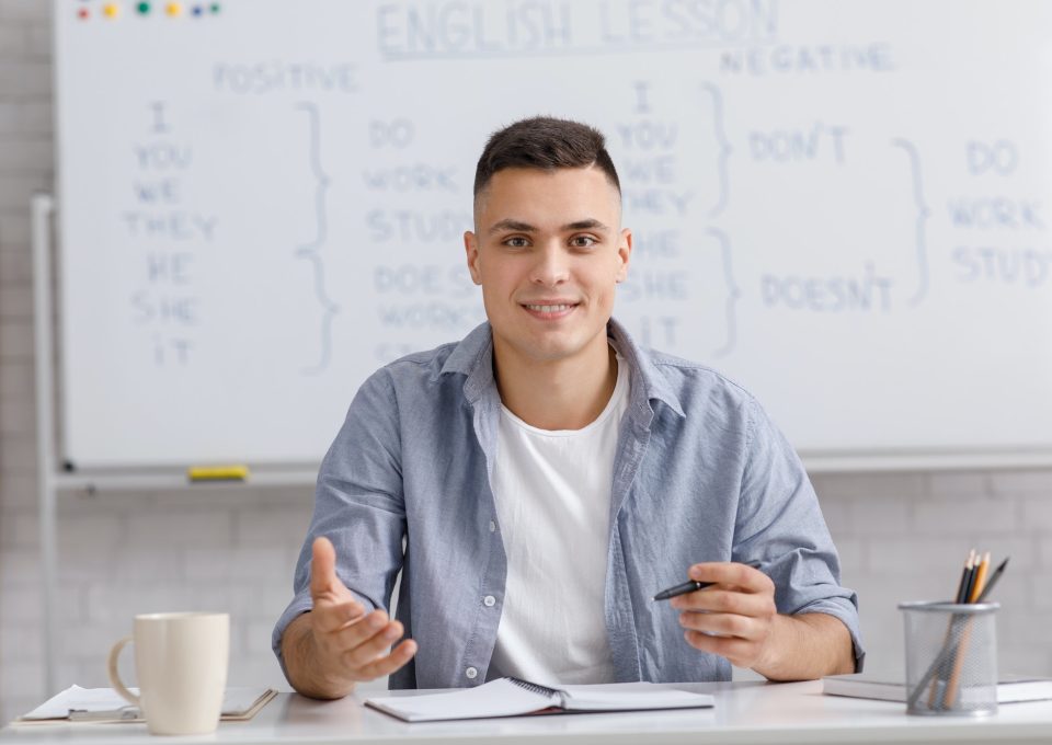 Online teacher speaking by webcam, sitting at table in home office and explaining rules english