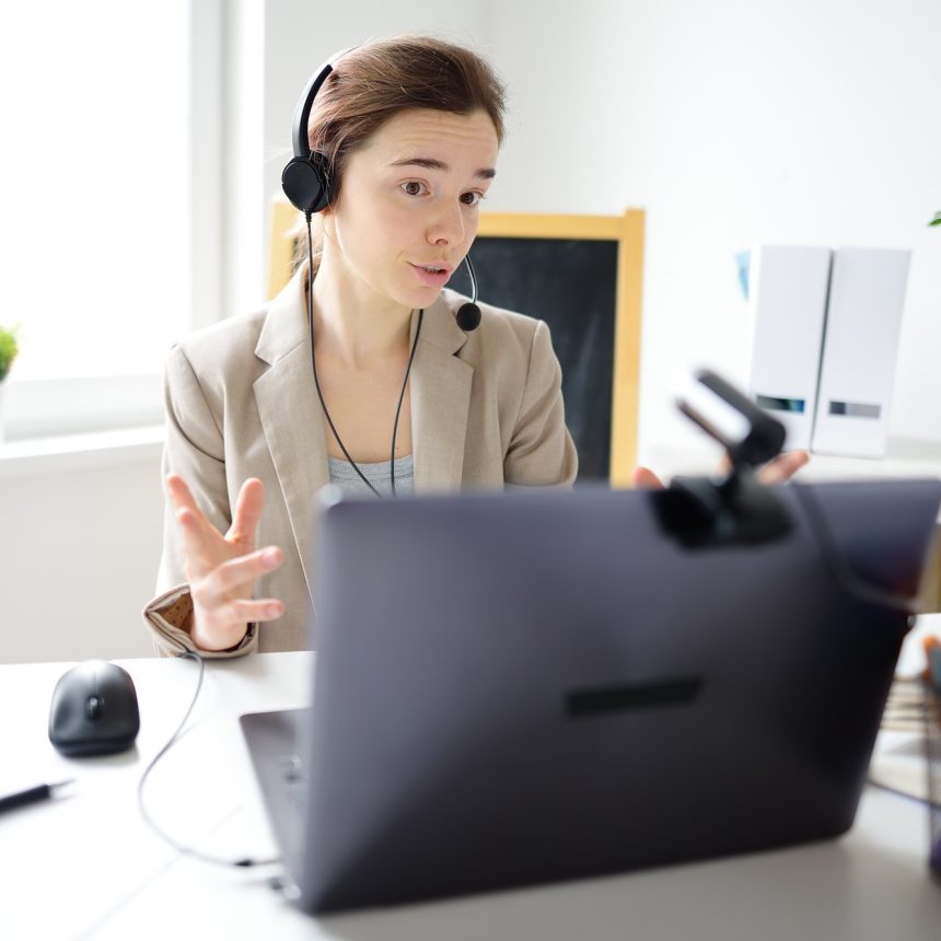 Young woman is learning language with laptop computer, camcorder and headphone online at home.